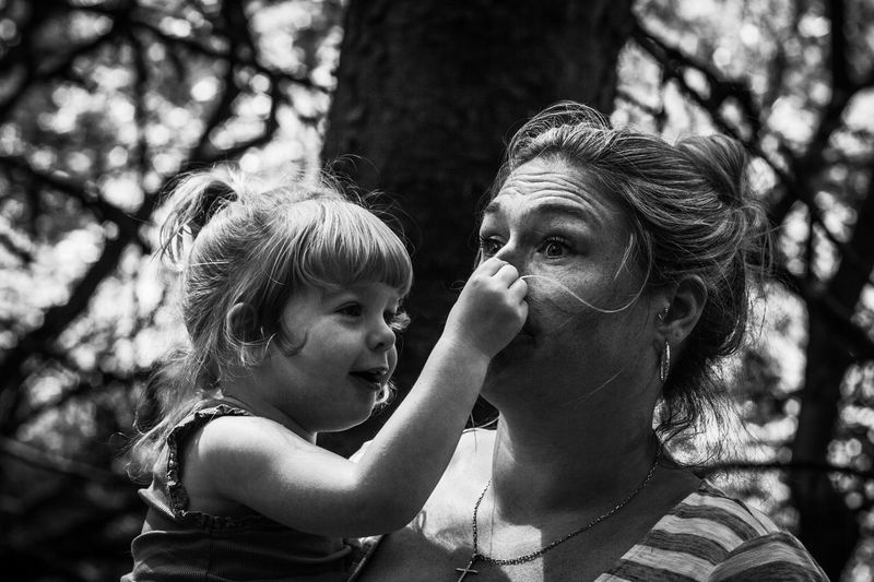 Mother and daughter against tree