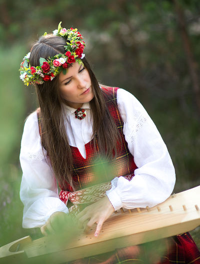 Beautiful musician wearing flowers wreath while playing string instrument
