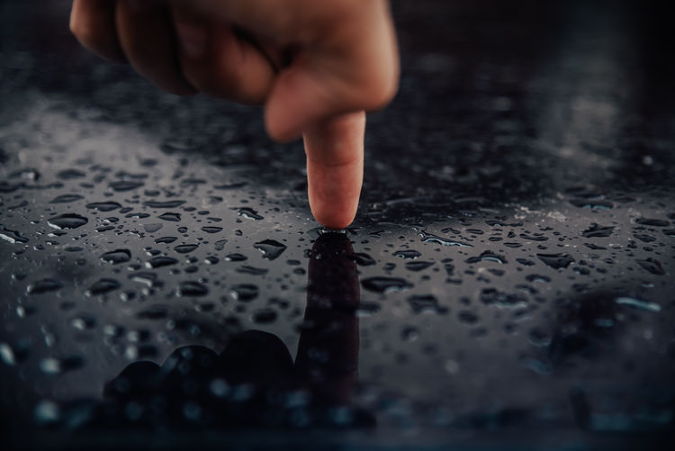 Closeup view of human finger on wet surface