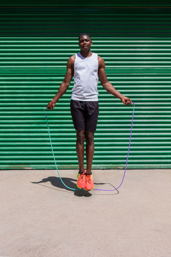 Focused african american male athlete jumping rope during cardio workout on sunny day in city