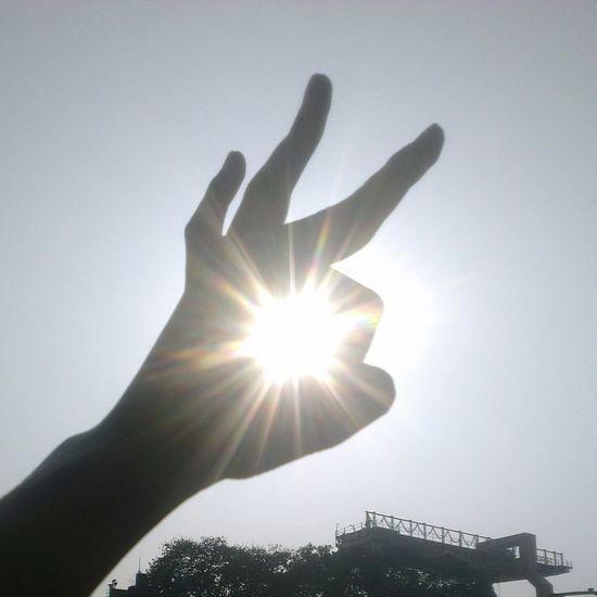Low angle view of human hand against sun