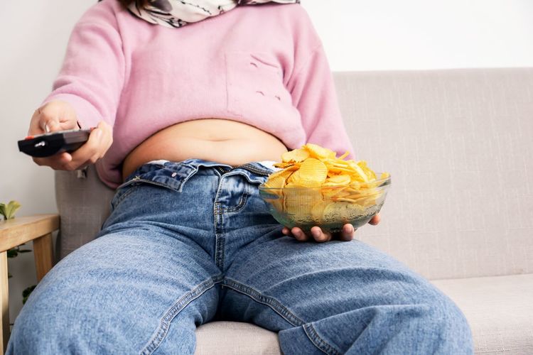 Midsection of woman holding while sitting on sofa at home