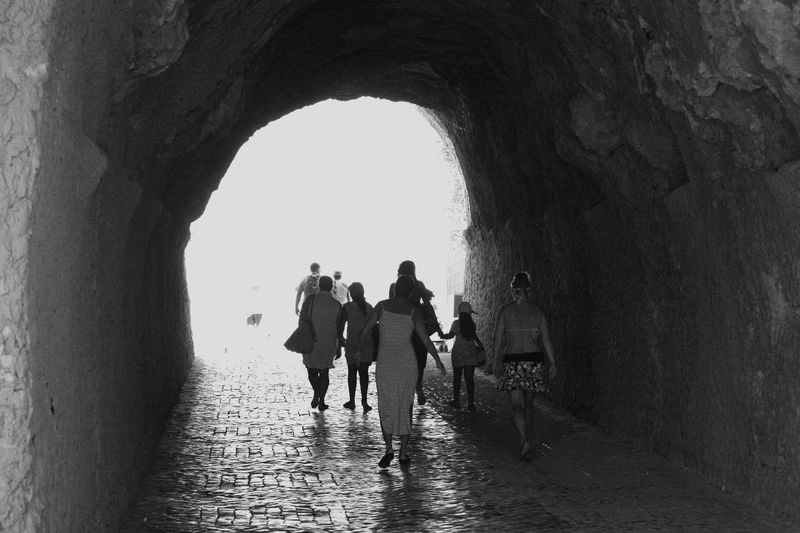 Rear view of people walking under tunnel