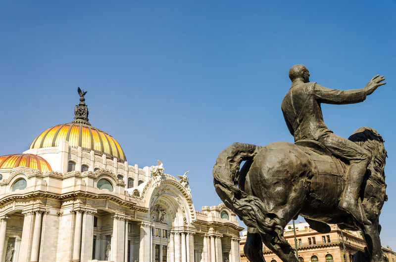 Low angle view equestrian statue of palacio de bellas artes against clear sky