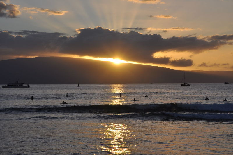 Watching the sunset at the beach in hawaii, sun poking through the clouds.