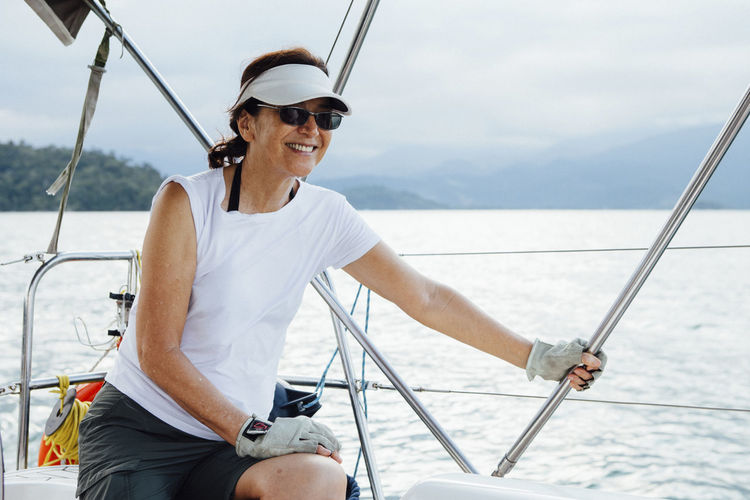 Happy woman sitting in sailboat on sea