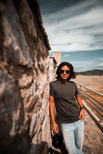 Portrait of man wearing sunglasses while standing by wall