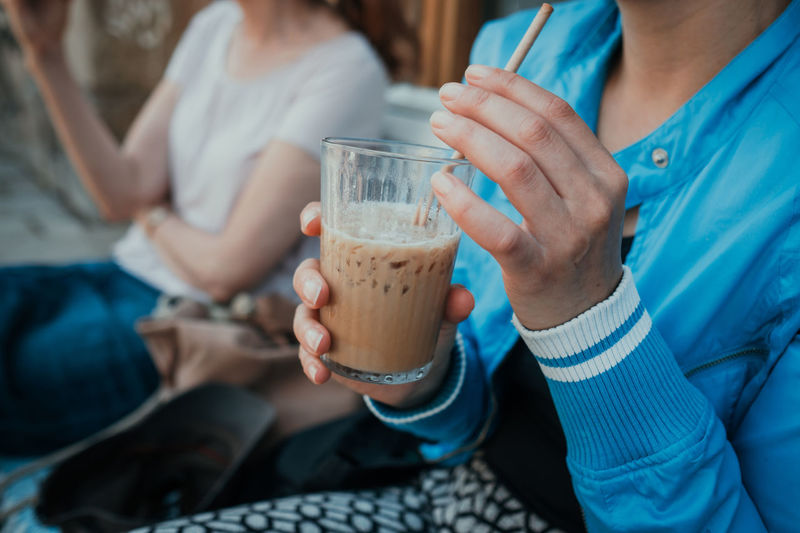 Midsection of woman holding iced coffee
