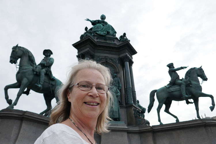 Portrait of smiling woman standing against statues at hofburg palace