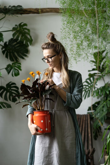Beautiful woman standing by potted plant