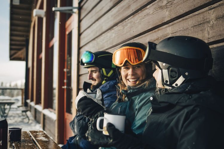 Happy male and female friends spending leisure time while having coffee at ski resort