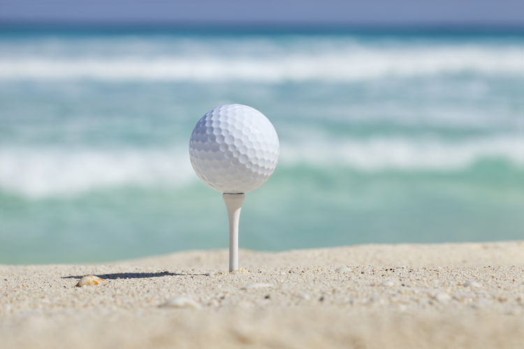 Golf ball on tee at beach