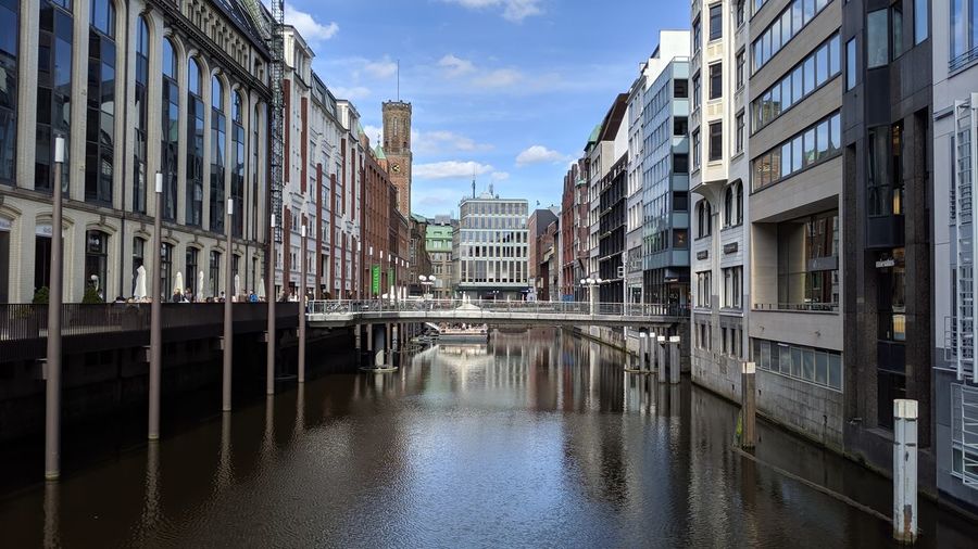Canal amidst buildings in city against sky