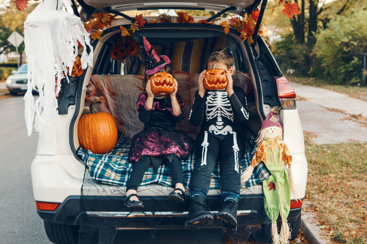 Cute kids wearing costume sitting in car trunk