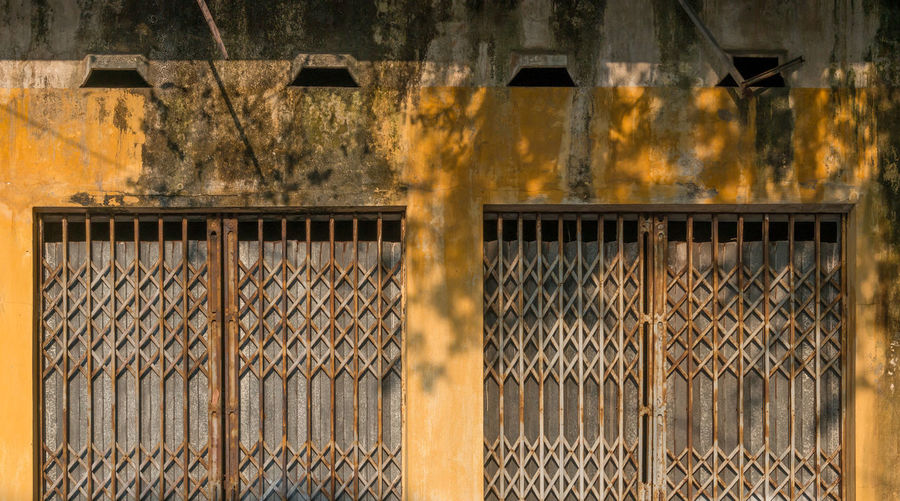 Full frame shot of rusty metal fence against old building