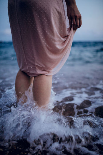 Low section of woman standing in sea