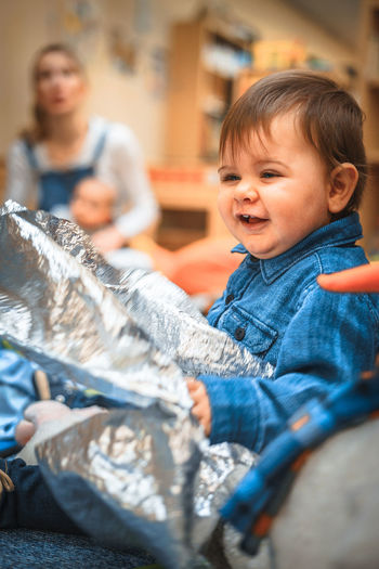Cheerful baby boy playing with foil at home
