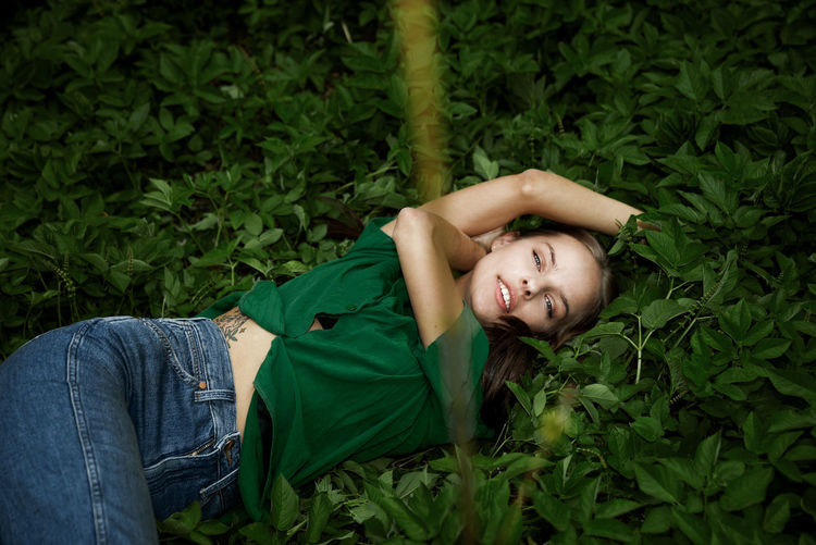 Low angle view of young woman standing amidst plants