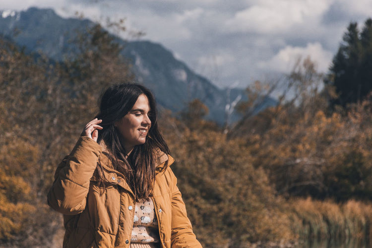 Beautiful young woman wearing autumn clothes, enjoying sunlight in mountains