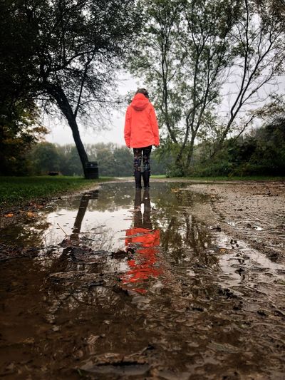 Rear view of person standing in puddle