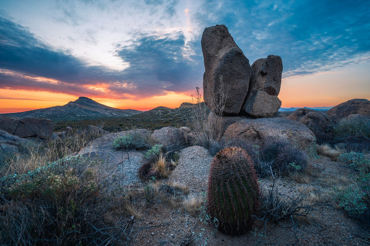 Dramatic sunset with massive boulders and cactus overlooking brown's mountain in the mcdowell sono