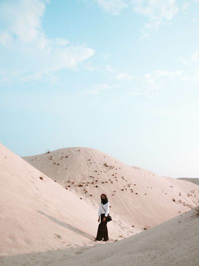 Woman standing on desert against sky