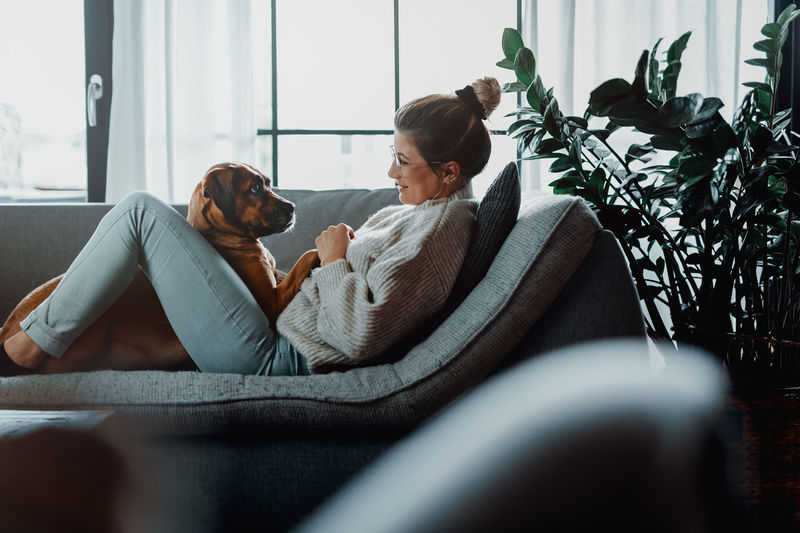 Woman with dog on sofa at home
