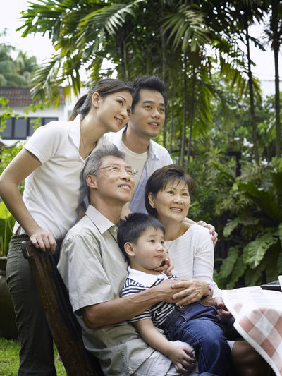 Smiling multi-generation family sitting at table in yard