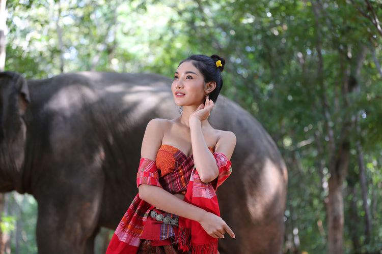 Young woman standing by elephant