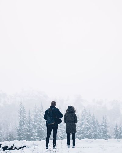 Rear view of man and woman standing on snow covered landscape