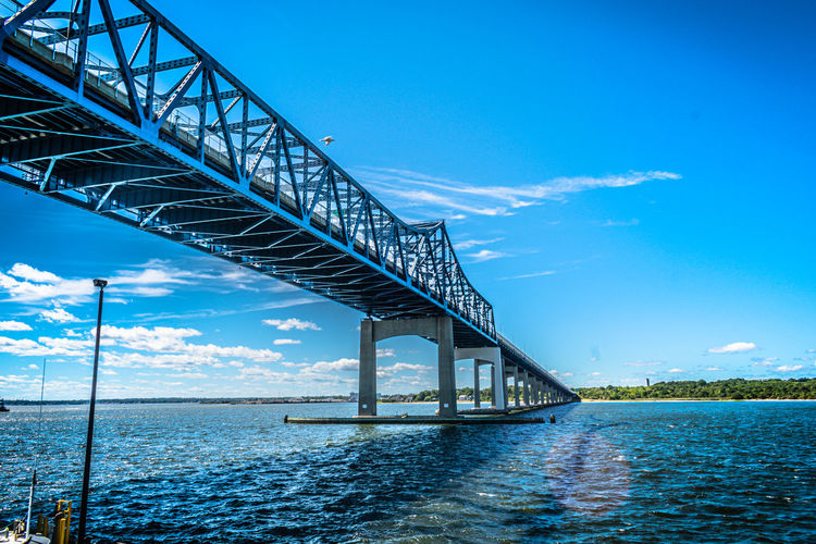 Low angle view of bridge over sea against blue sky