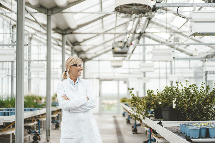 Cheerful scientist with arms crossed in plant nursery