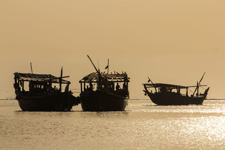 Three fishing boats in silhouette