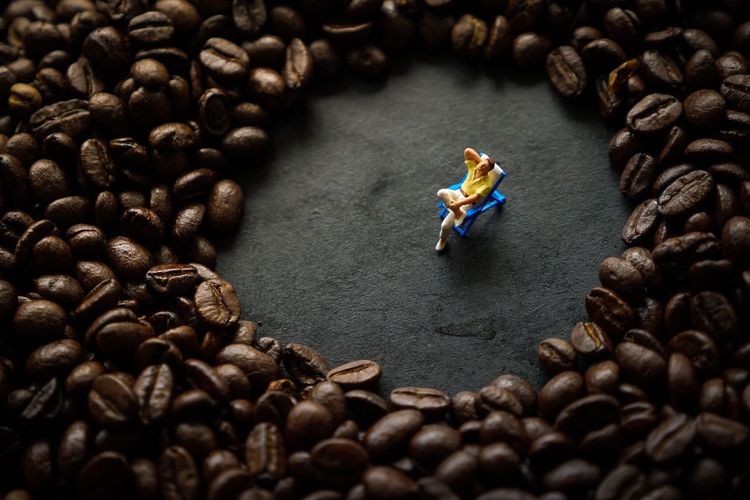 High angle view of figurine amidst coffee beans on table