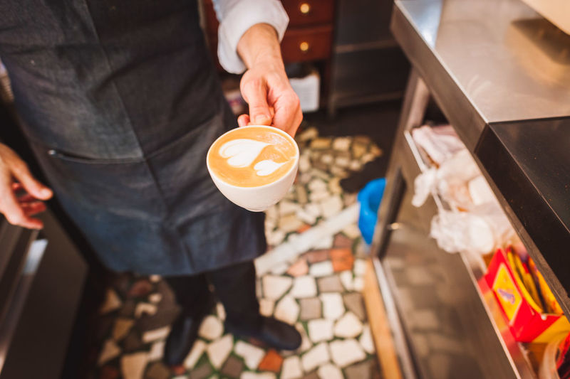 Close-up of barista holding coffee cup at cafe