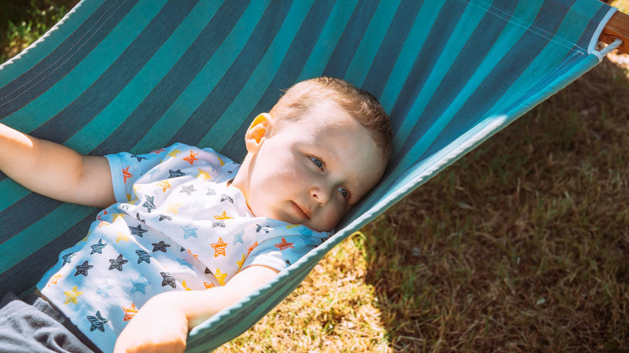 Portrait of cute baby lying on hammock outdoors