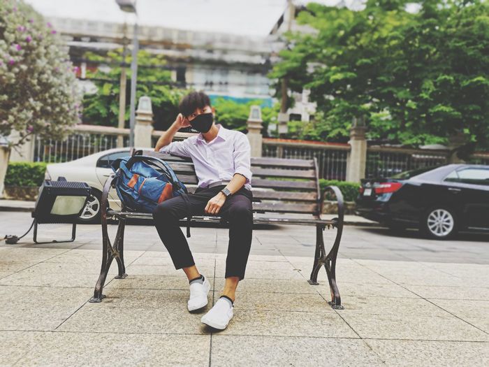 Full length of men sitting on sidewalk in city