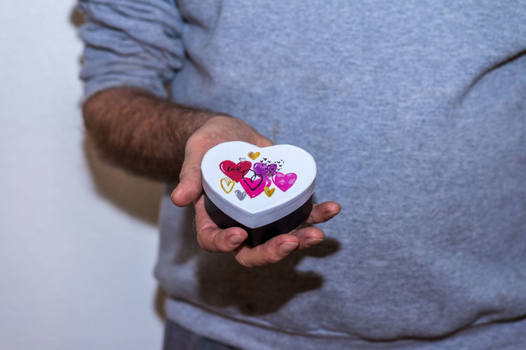 Midsection of man holding heart shape container