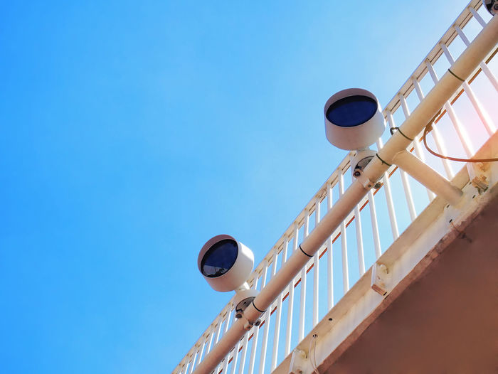 Low angle view of outdoor electric lamps against clear blue sky