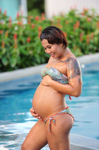 Pregnant woman standing by swimming pool