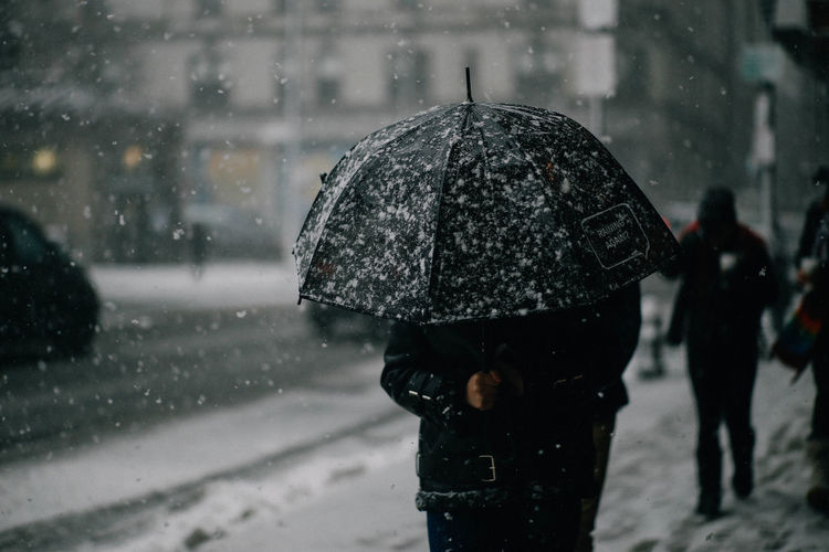 Person carrying umbrella walking on sidewalk during winter