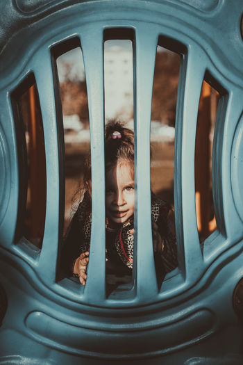 Portrait of girl looking through fence