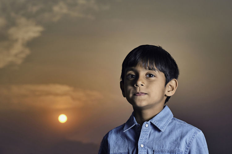 Portrait of boy standing against sky during sunset