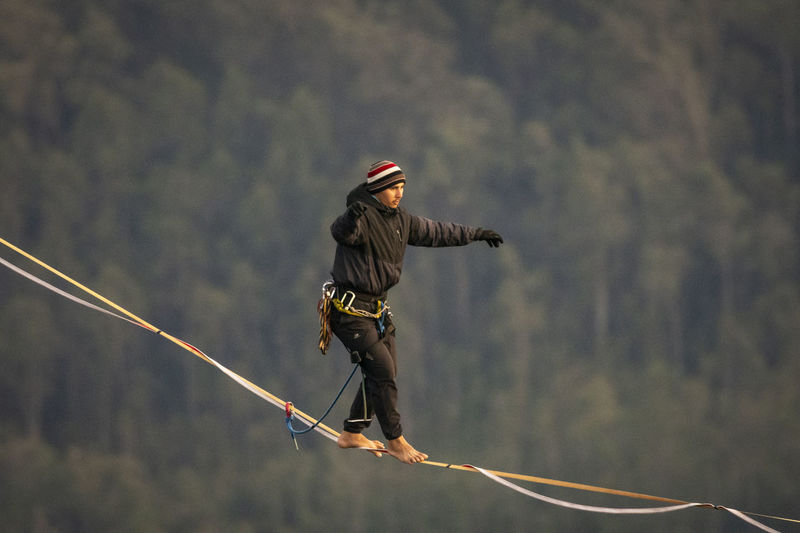 Rear view of man skateboarding on rope