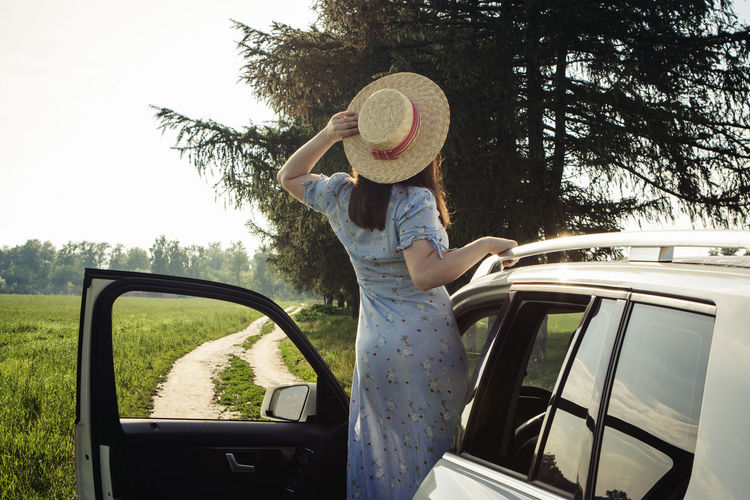 Woman in hat at the car in non-urban scene