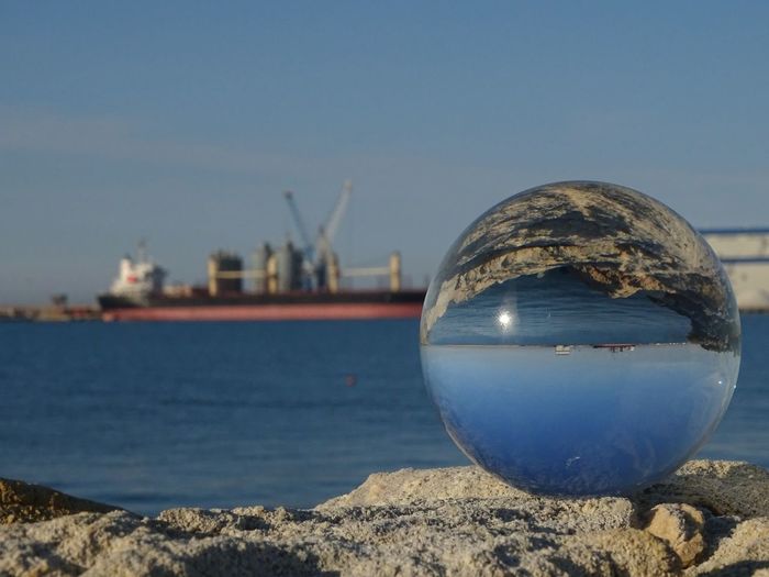 Close-up of crystal ball on rock at beach against clear sky