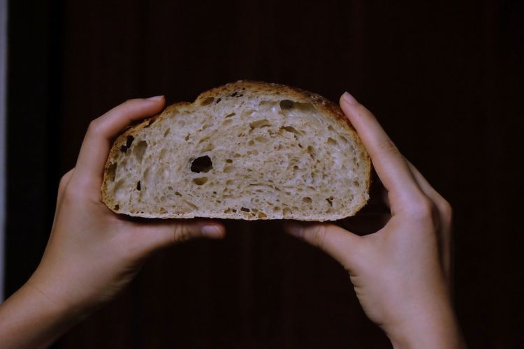Close-up of hand holding bread against black background