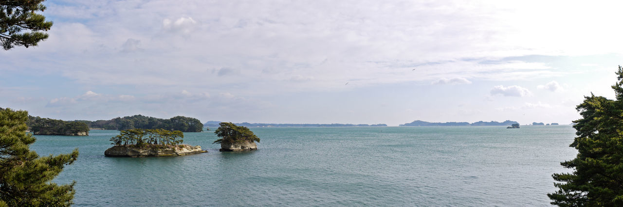 Panoramic aerial view of sea with small islands against cloudy sky
