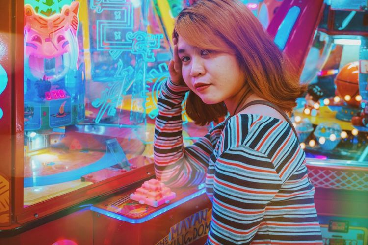 Girl sitting on an arcade game while looking at the camera