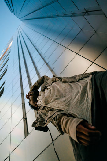 Low angle view of man working on building against sky